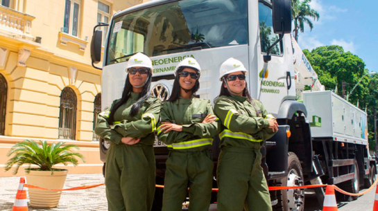 Foto de mulher eletricistas uniformizada com caminhão ao fundo