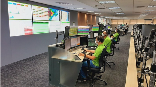 Foto de colaboradores trabalhando em computadores dentro de centro de operações