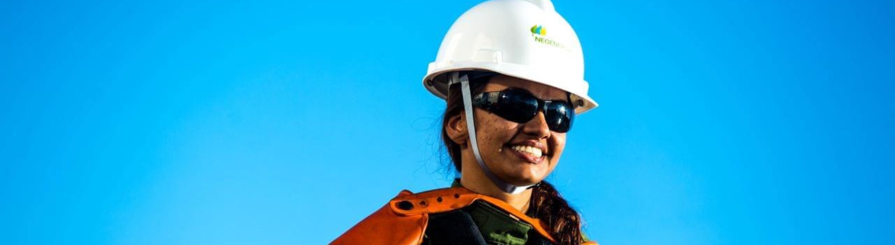 Foto com fundo azul e uma mulher sorrindo com um capacete branco da Neoenergia