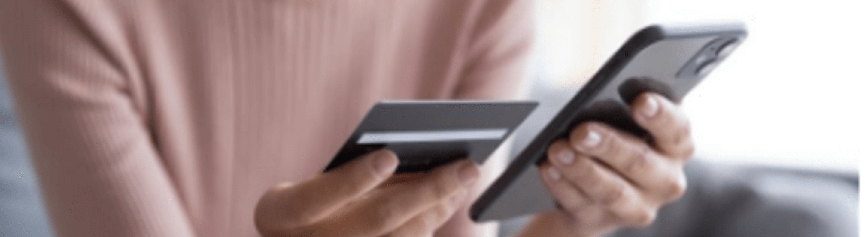 Uma pessoa segurando um celular e um cartão de banco
