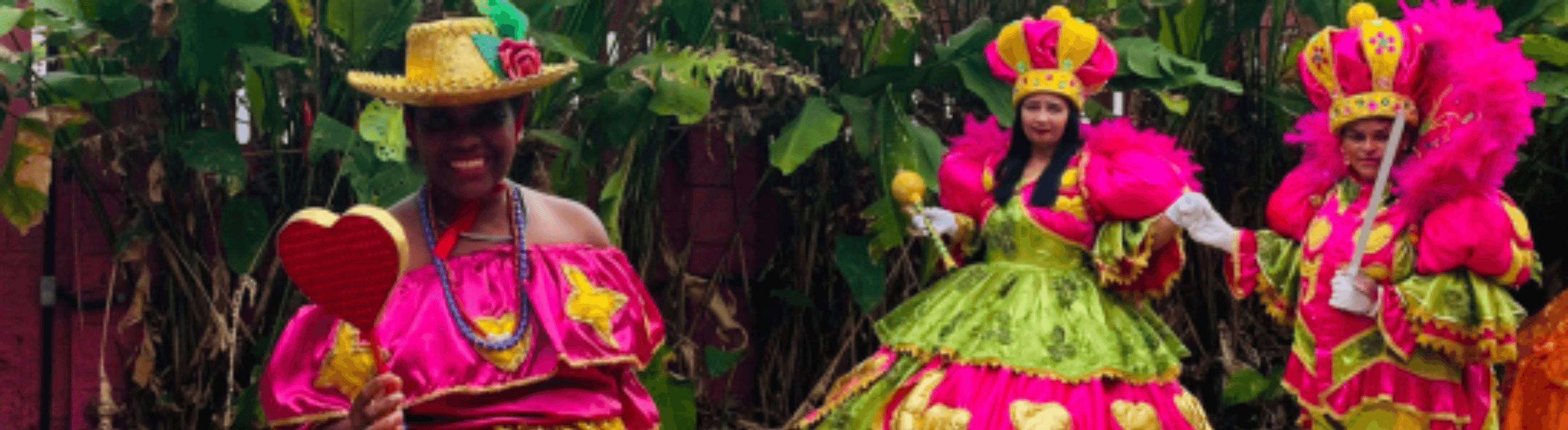 Três mulheres adultas com roupas alegóricas nas cores verde e rosa