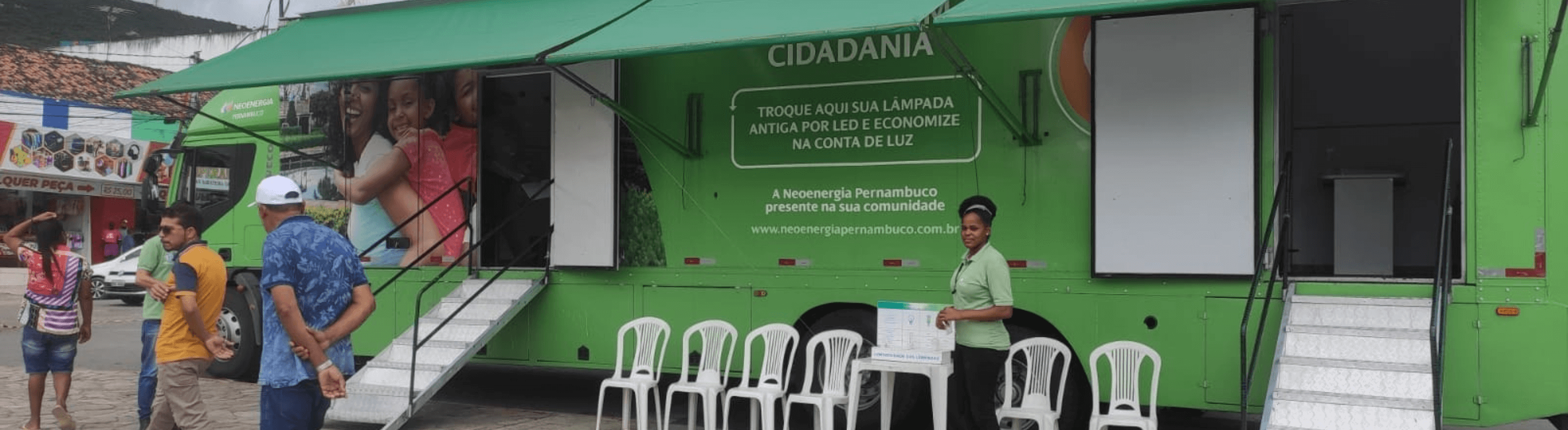 Caminhão do Projeto Energia Com Cidadania estacionado atendendo clientes. A cor predominante é verde