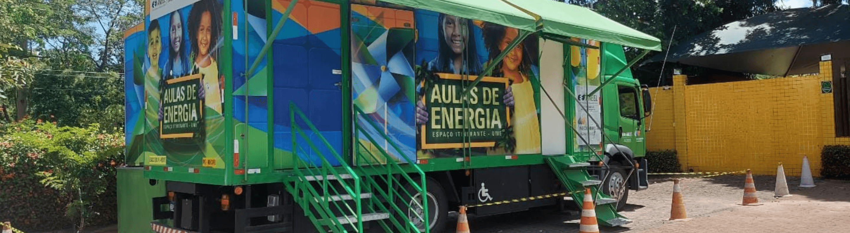 Caminhão do Projeto Aulas de Energia da Neonergia Pernambuco estacionado, com as cores verde e azul predominante