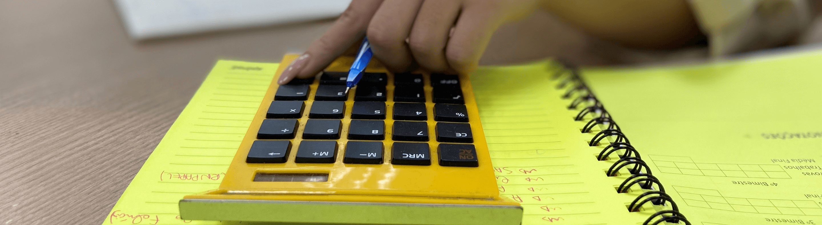 Um caderno de anotação de folhas amarela e uma calculadora amarela