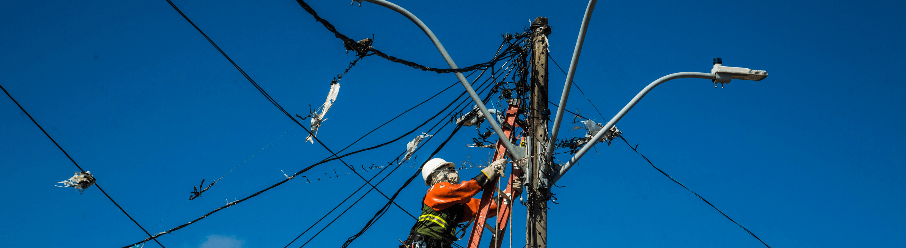 Eletricista da Neoenergia instalando iluminação em poste