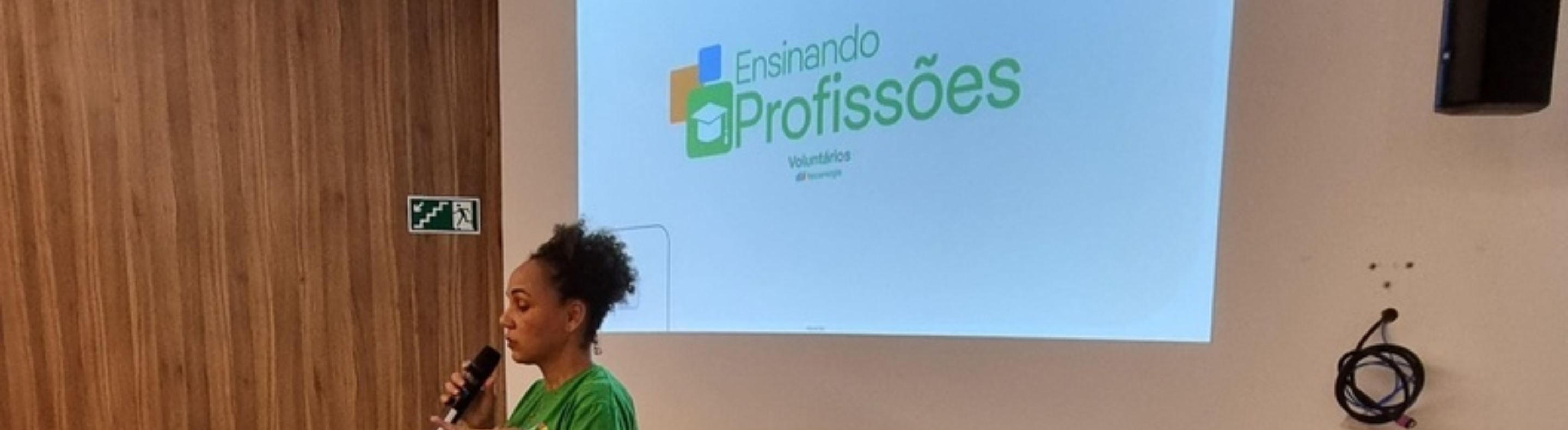 Voluntária da Neoenergia Coelba no auditório da empresa fazendo discurso
