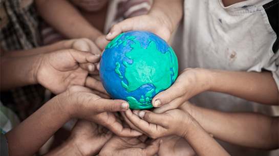foto de várias mãos de crianças segurando o protótipo do planeta Terra
