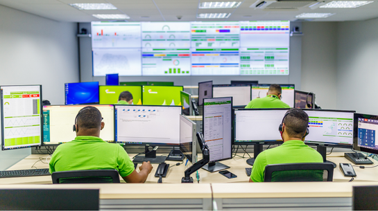 Foto de colaboradores trabalhando em computadores de centro de monitoramento