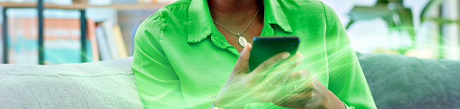 Mulher de camisa verde segurando celular nas mãos
