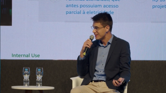Foto do executivo Heron falando ao microfone durante palestra