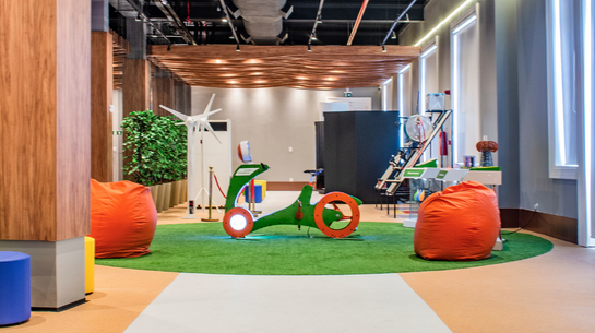Photo of inside the museum in colorful space, with bicycle-like apparatus and puffs