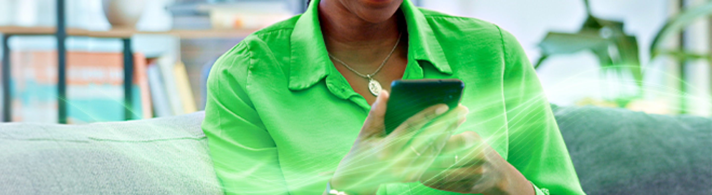 Mulher de camisa verde segurando celular nas mãos