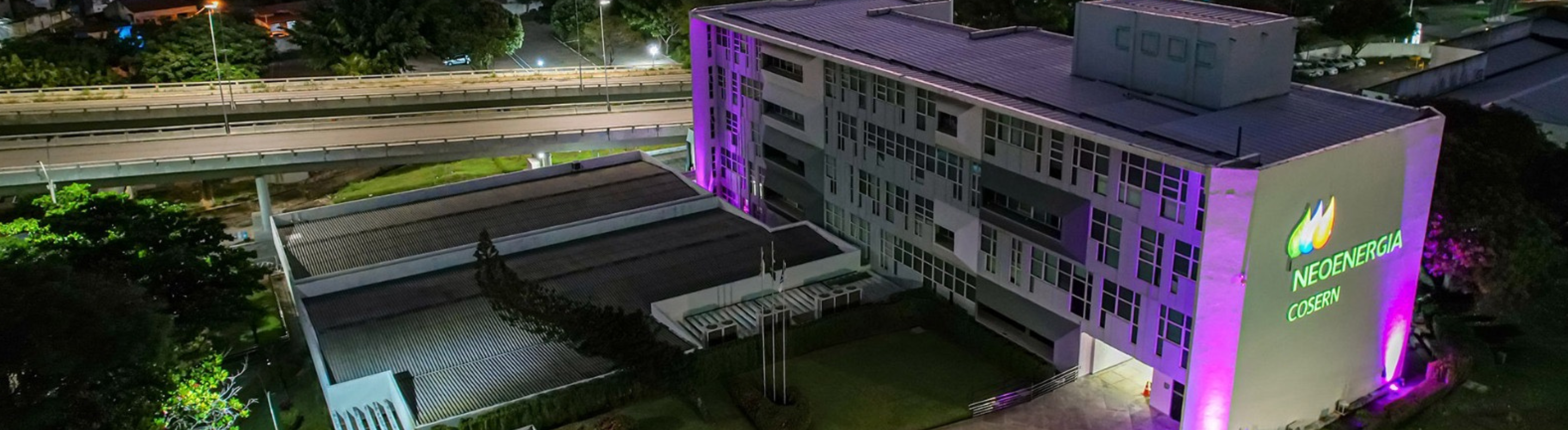 Imagem mostra fachada da Neoenergia Cosern iluminada em tom de rosa em alusão à campanha contra o câncer de mama
