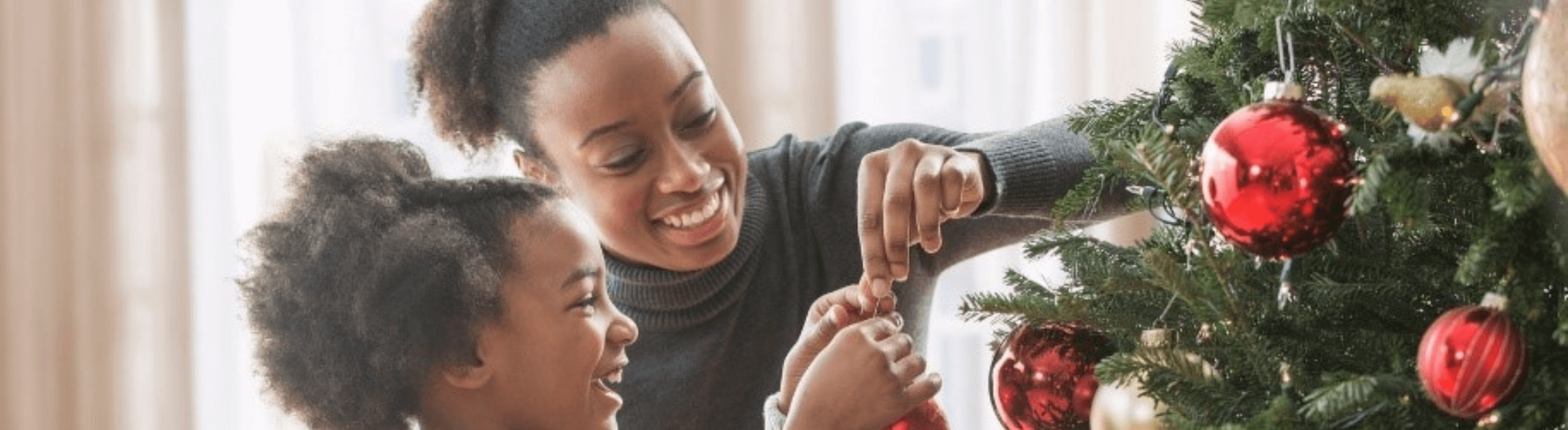 Uma mulher e uma criança negras decorando uma árvore de Natal