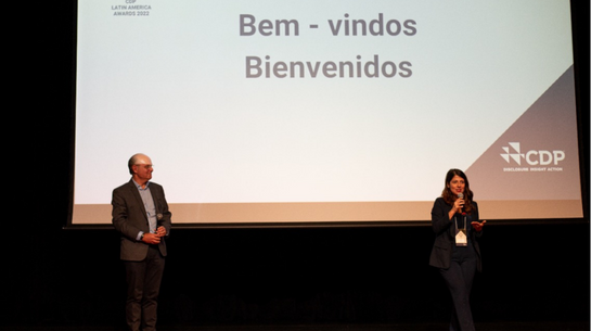 Foto de palco do evento com dois executivos durante palestra
