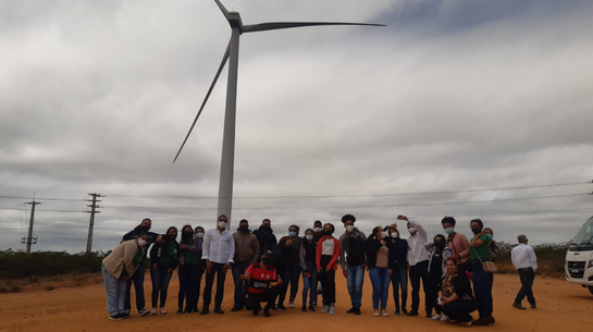 Foto de estudantes reunidos em frente a aerogerador