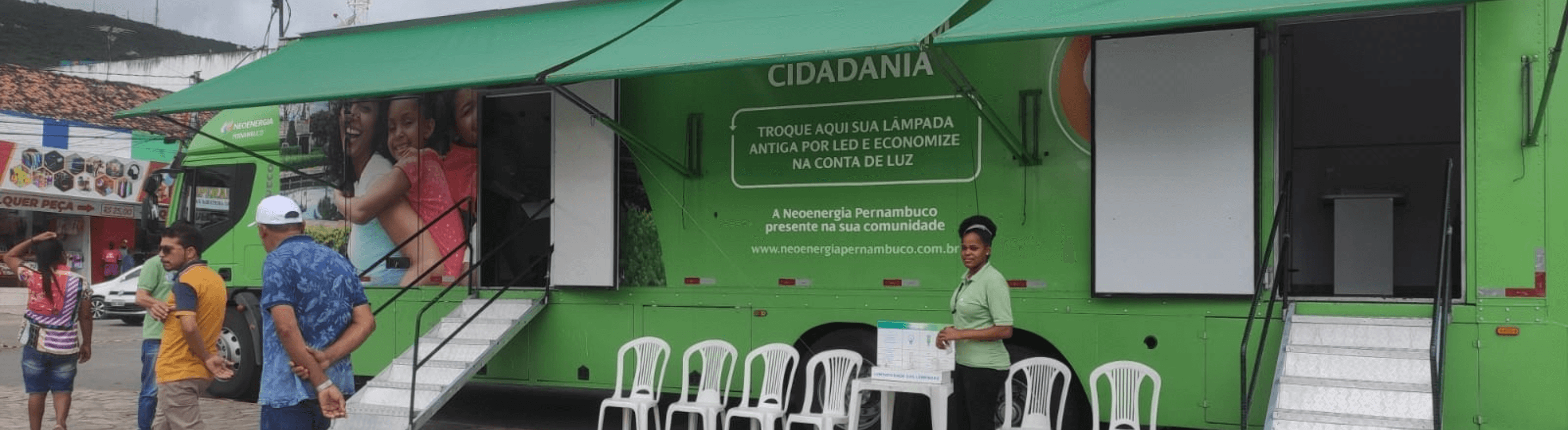 Caminhão verde do Projeto Energia Com Cidadania da Neoenergia Pernambuco estacionado atendendo clientes